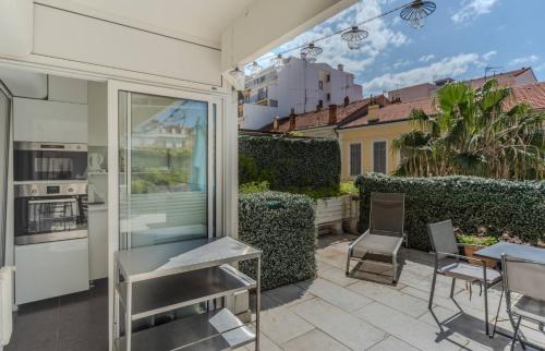 un patio avec une cuisine, une table et des chaises dans l'établissement Luxueux 3 Chambres Terrasse de 90m hypercentre - Wifi Clim - 6 pers, à Cannes