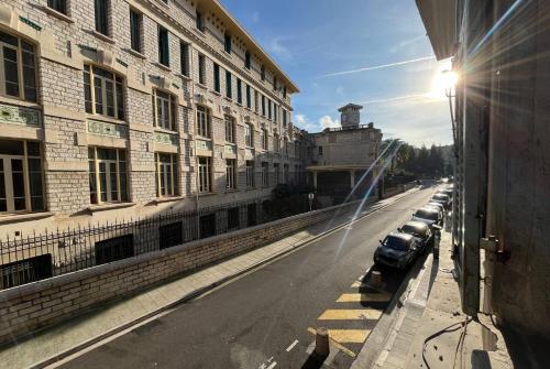 une rue avec des voitures garées sur le côté d'un bâtiment dans l'établissement Studio Nice Masséna - Coulée Verte, à Nice