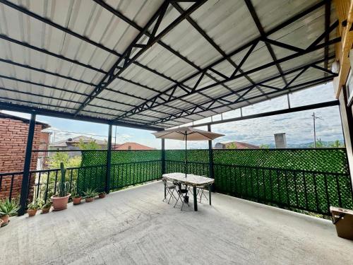 a patio with a table and umbrella on a balcony at Guest House AMO in Kutaisi