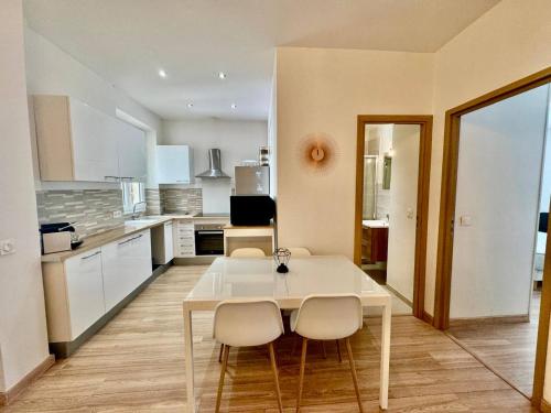 - une cuisine avec une table et des chaises blanches dans la chambre dans l'établissement 3 pièces Nice Port Smolett, à Nice