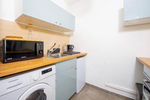 une cuisine avec un micro-ondes et un lave-linge dans l'établissement Studio Port Golfe-Juan Parking Wifi Climatisation Terrasse, à Vallauris