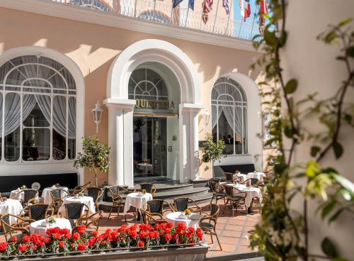 a restaurant with tables and chairs and red flowers at Hotel Quisisana in Capri