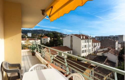 un balcon avec une table, des chaises et un parasol dans l'établissement Le Saint Paul - 2 chambres - 2 salles de bains - WIFI climatisation, à Cannes