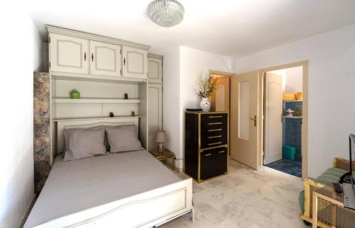 - une chambre avec un lit blanc et une commode noire dans l'établissement Studio Fenelon terrasse et Parking Cannes, à Cannes