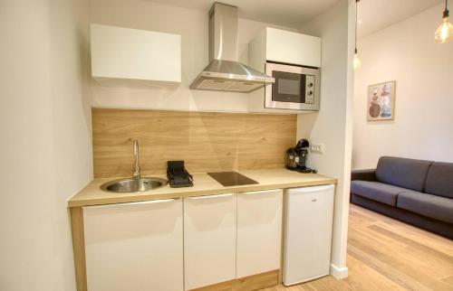 une petite cuisine avec un évier et un canapé dans l'établissement Elégant Studio moderne Wifi Proche suquet - LIMESTAY, à Cannes