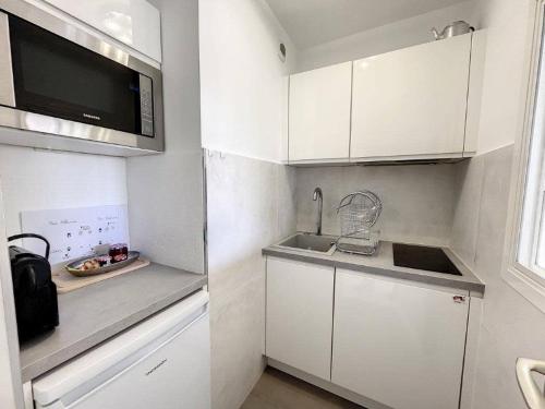 Il comprend une petite cuisine blanche avec un évier et un four micro-ondes. dans l'établissement STUDIO MIDI MAGRET Cannes, à Cannes