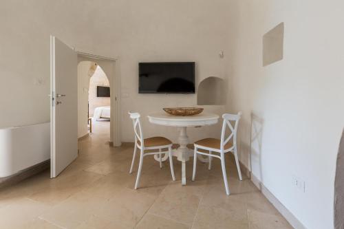 a white dining room with a white table and chairs at Casale Amenola by Perle di Puglia in Ostuni