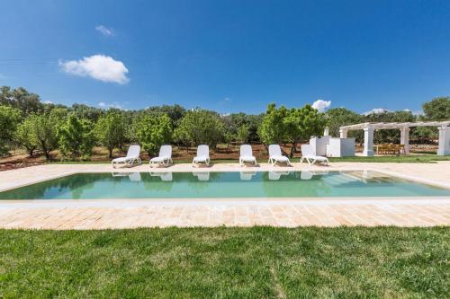 a swimming pool with lounge chairs in the grass at Casale Amenola by Perle di Puglia in Ostuni