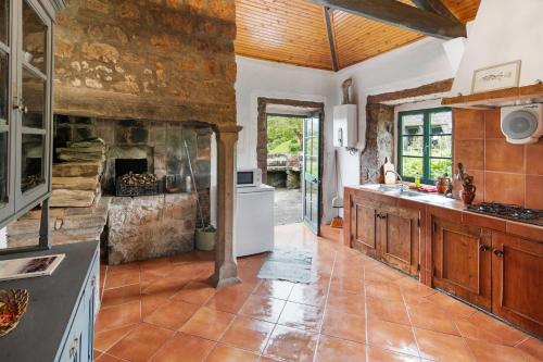 a kitchen with a stone wall and a fireplace at Quinta das Queimadas in Nordeste