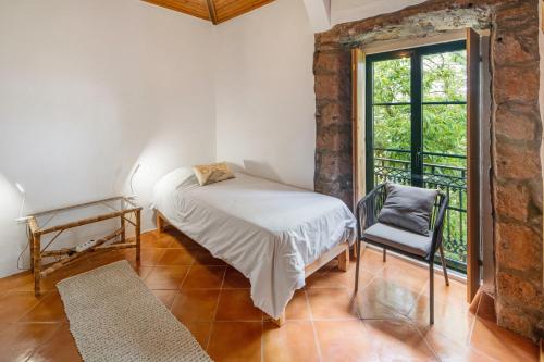 a bedroom with a bed and a window and a chair at Quinta das Queimadas in Nordeste