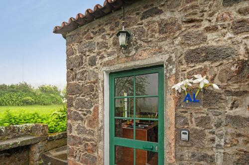 a stone building with a green door and a window at Quinta das Queimadas in Nordeste