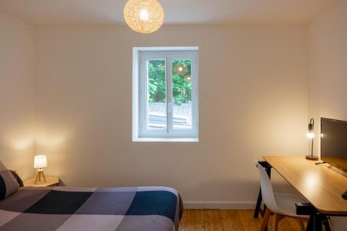 een slaapkamer met een bed, een bureau en een raam bij les loges de jeanne in Orléans