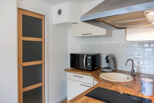 une cuisine avec un évier et un micro-ondes dans l'établissement les loges de jeanne, à Orléans