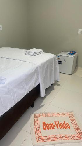 a bed with a white blanket on top of it at Vila Aconchego in Bragança