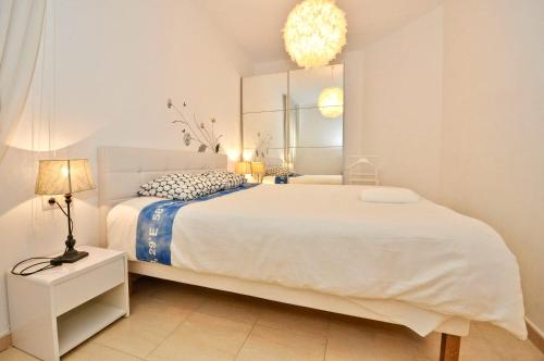 a bedroom with a large white bed and a mirror at Apartment Verano Go2lloret in Lloret de Mar