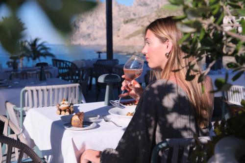 a woman sitting at a table with a glass of wine at El Vicenç de la Mar - Adults Only - Over 12 in Pollença
