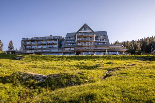 a large building on top of a grassy hill at Erlebachova Bouda, hotel - Resort Svatý František in Špindlerův Mlýn