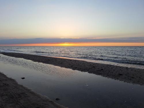 a beach with the sun setting over the ocean at Apartment Ostseenordstern Kühlungsborn in Bastorf