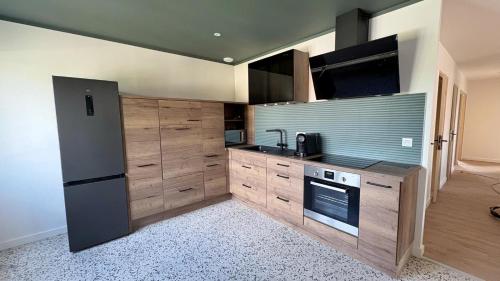 une cuisine avec des armoires en bois et un réfrigérateur noir dans l'établissement Appartement 3 chambres avec jardin, à Langogne