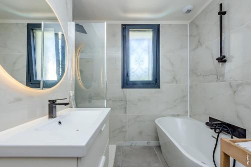 La salle de bains blanche est pourvue d'une baignoire, d'un lavabo et d'une baignoire. dans l'établissement Maison de ville tout confort 10 personnes avec piscine, à Montauban