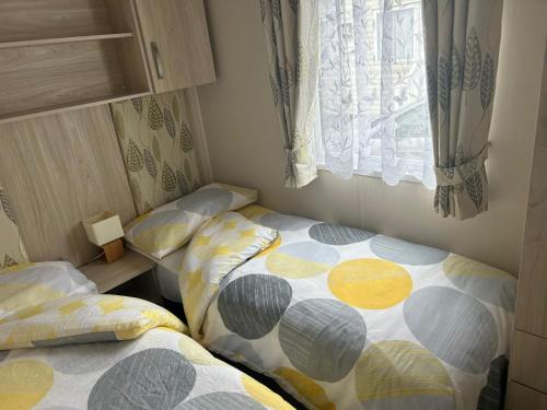 2 aparte bedden in een kleine kamer met een raam bij Ardmachree in Burton Bradstock