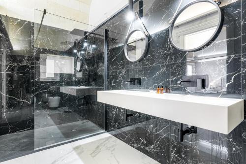 Un baño de mármol negro con lavabo y espejos. en Masseria Tenuta Quintino, en Torre Lapillo