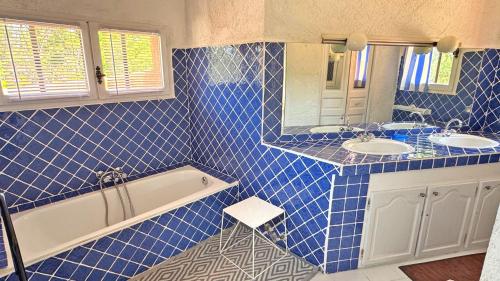 une salle de bain carrelée bleue avec deux lavabos et une baignoire dans l'établissement Bastide Coriolan, à Préconil
