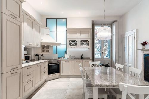 een keuken met witte kasten en een tafel met stoelen bij Cedro Apartment by Quokka 360 - designer flat in Como in Como