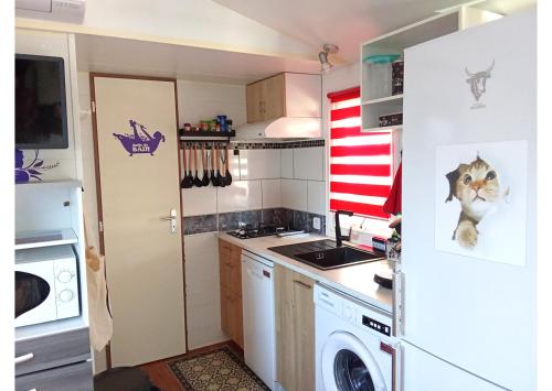 Il comprend une petite cuisine équipée d'un réfrigérateur et d'un lave-linge. dans l'établissement Mobil home - Clim, TV, LV, LL - Camping Vic-la-Gardiole 4 étoiles - MH-A006, à Vic-la-Gardiole