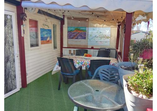 un patio avec une table et des chaises sur un porche dans l'établissement Mobil home - Clim, TV, LV, LL - Camping Vic-la-Gardiole 4 étoiles - MH-A006, à Vic-la-Gardiole