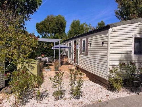 une maison avec une terrasse à côté d'un bâtiment dans l'établissement Chalet Melrose - Camping Parc Valrose, à La Londe-les-Maures