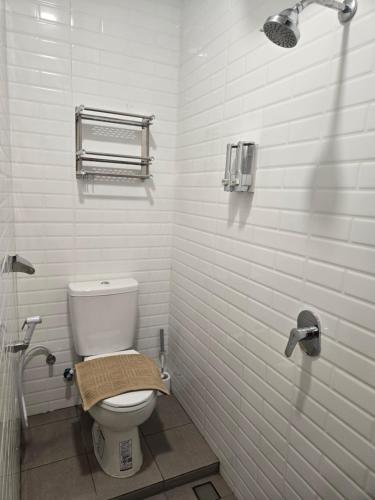 a white bathroom with a toilet and a shower at Rebahan Stay in Surabaya