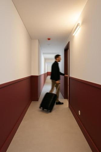 Un uomo che cammina lungo un corridoio con una valigia di Lisbon Serviced Apartments - Alvalade a Lisbona