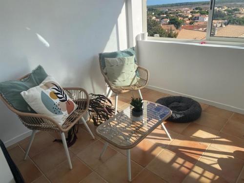 d'un balcon avec deux chaises, une table et une fenêtre. dans l'établissement Charmant appartement vue mer, à Frontignan