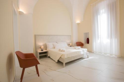 a white bedroom with a bed and a chair at Le Due Dimore in Collepasso