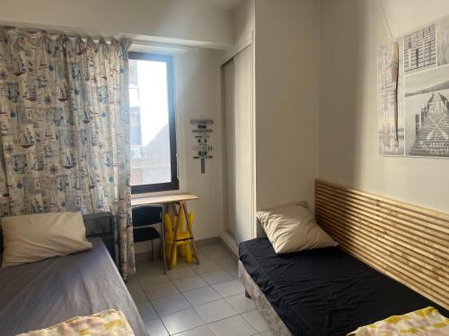 une chambre avec deux lits et une fenêtre dans l'établissement The Building Canebière, à Marseille