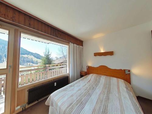une chambre avec un lit et une grande fenêtre dans l'établissement Appt 3 pièces 6 pers avec cheminée et navette proche Le Grand-Bornand - FR-1-241-47, au Grand-Bornand