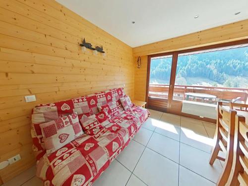 Cette chambre dispose d'un canapé et d'une grande fenêtre. dans l'établissement Appt cosy 3 pièces avec mezzanine - 6 couchages, parking, animaux admis - Grand Bornand - FR-1-241-104, au Grand-Bornand