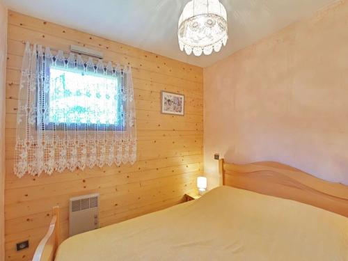 une chambre avec un lit, une fenêtre et un lustre dans l'établissement Grand-Bornand : Appt 2 pièces, 4 pers, jardin, garage, à 900m des pistes - FR-1-241-91, au Grand-Bornand