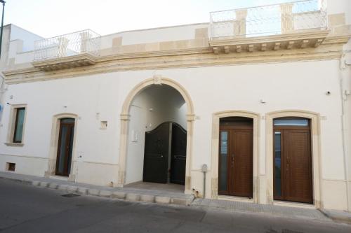 a white building with two doors and a balcony at Le Due Dimore in Collepasso