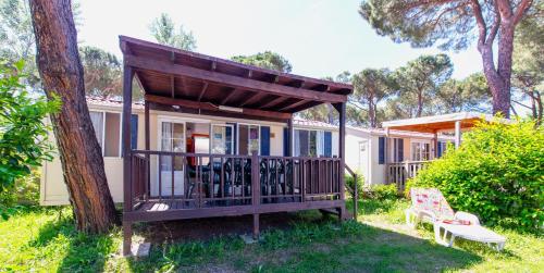 a small house with a deck and a tree at Camping Village Punta Navaccia in Tuoro sul Trasimeno