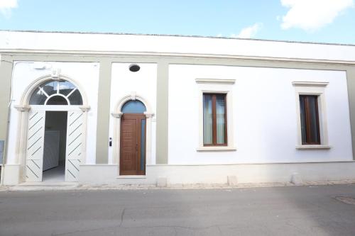 a white building with brown doors and windows at Le Due Dimore in Collepasso