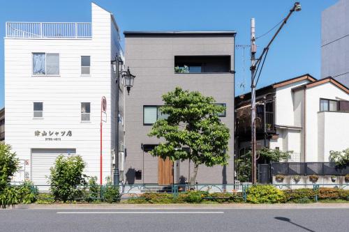 a tall white building with a tree next to a street at First Choice in Tokyo
