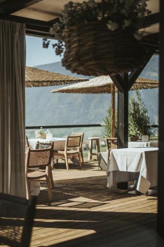 a patio with a table and chairs and a view of the water at Hotel KÜGLERHOF in Tirolo