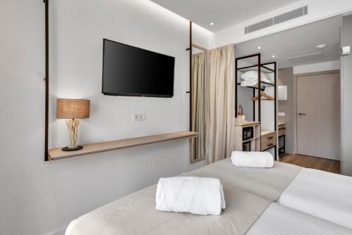 a bedroom with a large bed with a tv on the wall at Valentin Grand Park Suite Hotel in Paguera