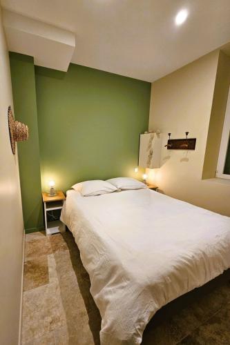 a bedroom with a white bed and a green wall at Le Loft de Genas - la Bastide, le Chalet, le Loft, le Mas, la Paillote in Genas