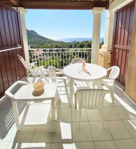 d'une terrasse avec des tables et des chaises blanches sur un balcon. dans l'établissement Apartment 2p with pool near the sea, à Saint-Raphaël