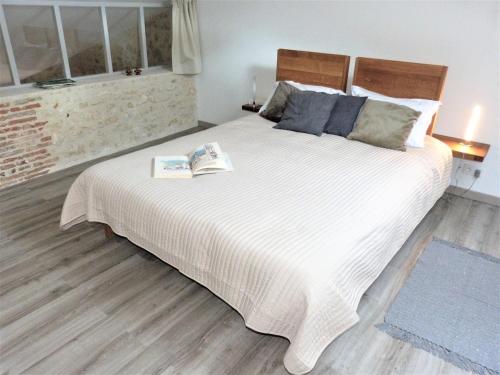une chambre avec un grand lit blanc avec un livre dessus dans l'établissement Le Quarante, à Périgueux