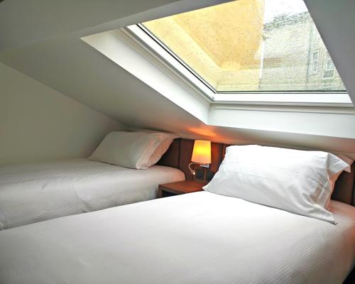 two beds in a small room with a skylight at Hôtel & Appartements Monsigny in Nice