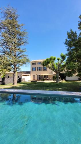 une grande piscine d'eau avec une maison en arrière-plan dans l'établissement Villa paisible en Provence, à Orange